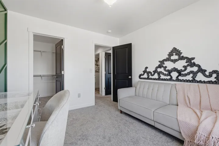 Carpeted room featuring a built-in closet with shelving, white trim, and dark interior doors