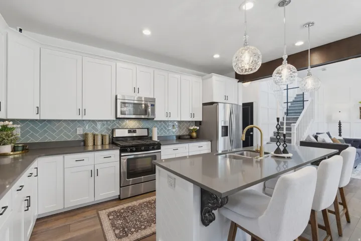 Kitchen featuring white shaker cabinetry, stainless steel appliances, a herringbone tile backsplash, gray countertops, and wood-finish flooring