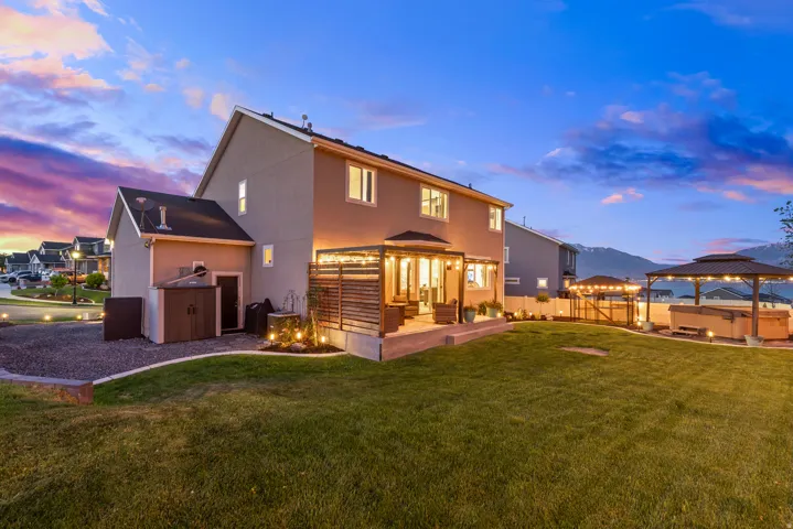 Expansive backyard featuring a manicured lawn, a concrete patio with a slatted privacy screen, and a gazebo