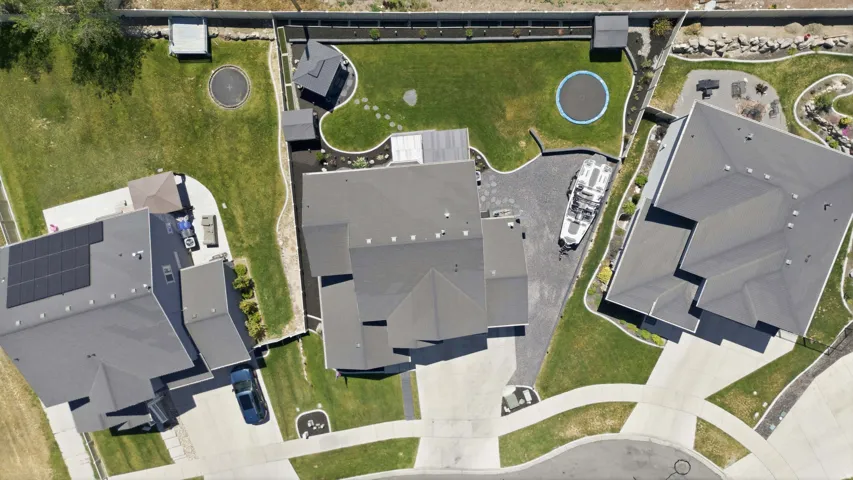 Expansive property featuring a large landscaped yard, paved driveway, multiple patio areas, and a structured roofline
