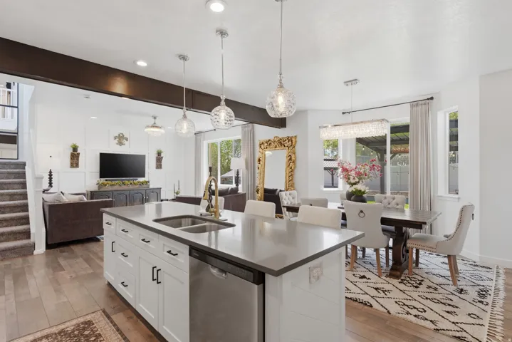 Open-concept kitchen and living area featuring a central island with integrated double sink, stainless steel appliances, and pendant lighting
