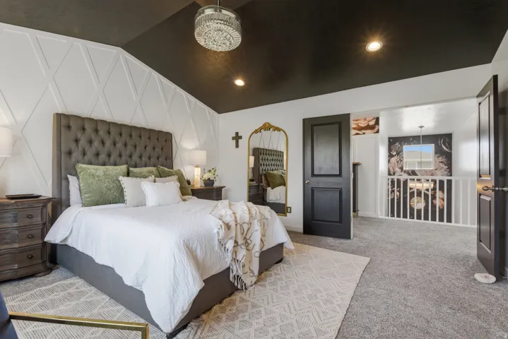 Vaulted ceiling with recessed lighting and a decorative chandelier, complemented by textured accent wall paneling