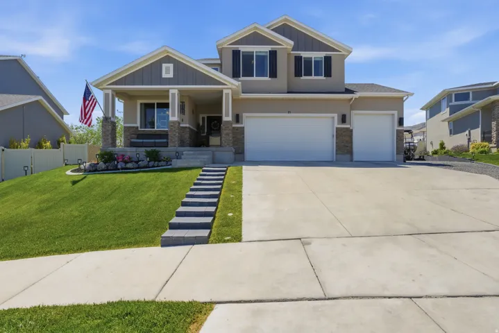 Two-story residence featuring a covered front porch with stone accents, a dual-door garage, and a concrete driveway