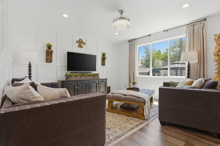 Living area featuring wood-finish flooring, a contemporary chandelier, recessed lighting, and a large window with natural light