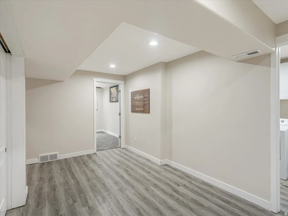 Finished lower level featuring wood-finish flooring, recessed lighting, and white trim