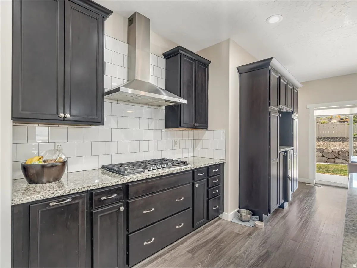 Kitchen featuring dark wood cabinetry, light-colored granite countertops, and a subway tile backsplash