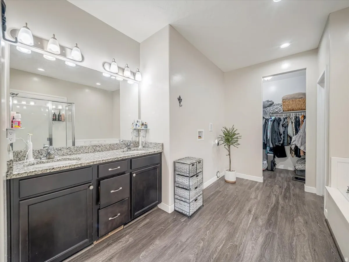 Bathroom featuring a dual vanity with granite-finish countertop, dark wood-finish cabinetry, and an oversized mirror