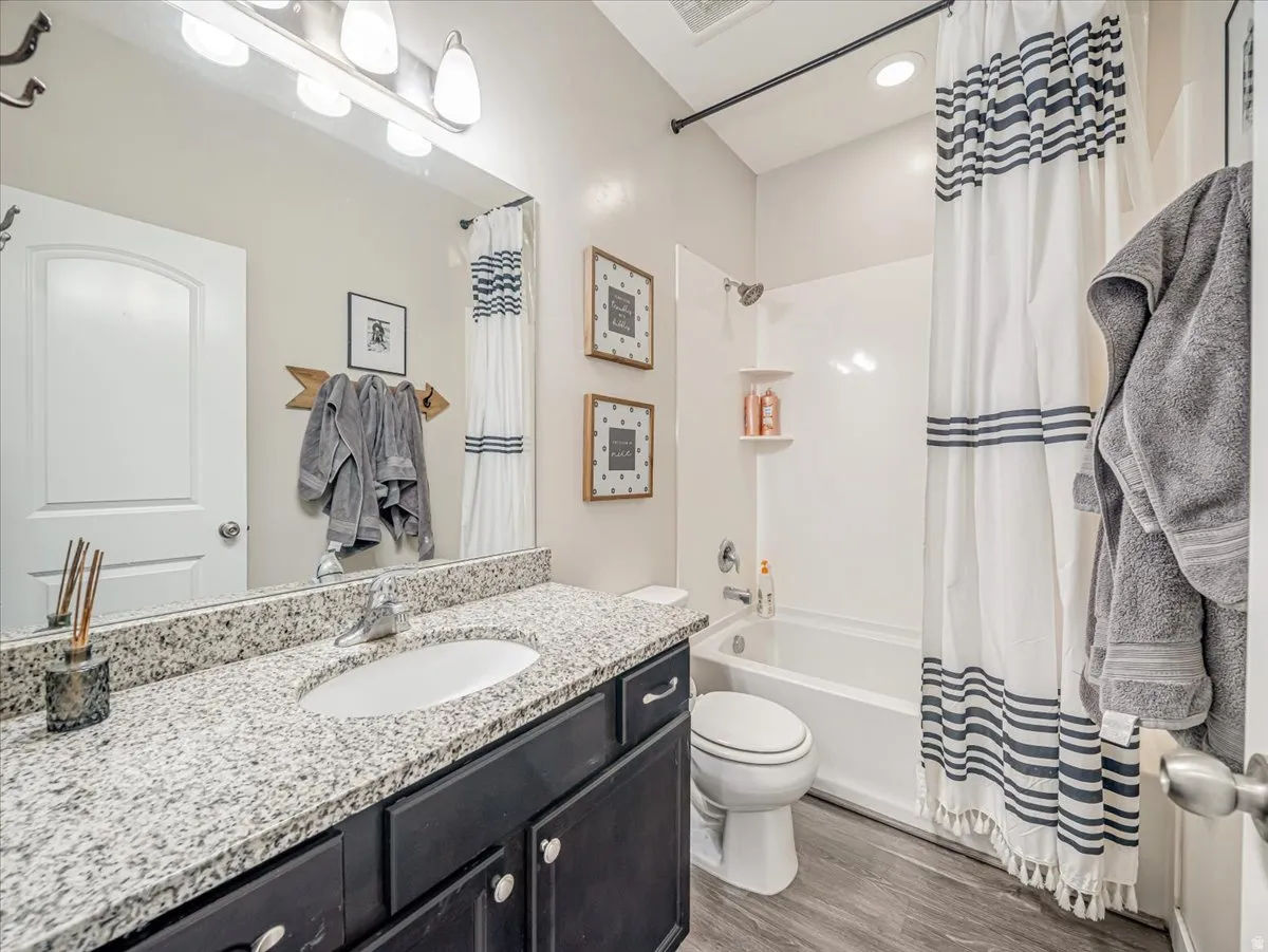 Bathroom featuring a dark wood-finish vanity with a light granite-finish countertop, undermount sink, and chrome faucet