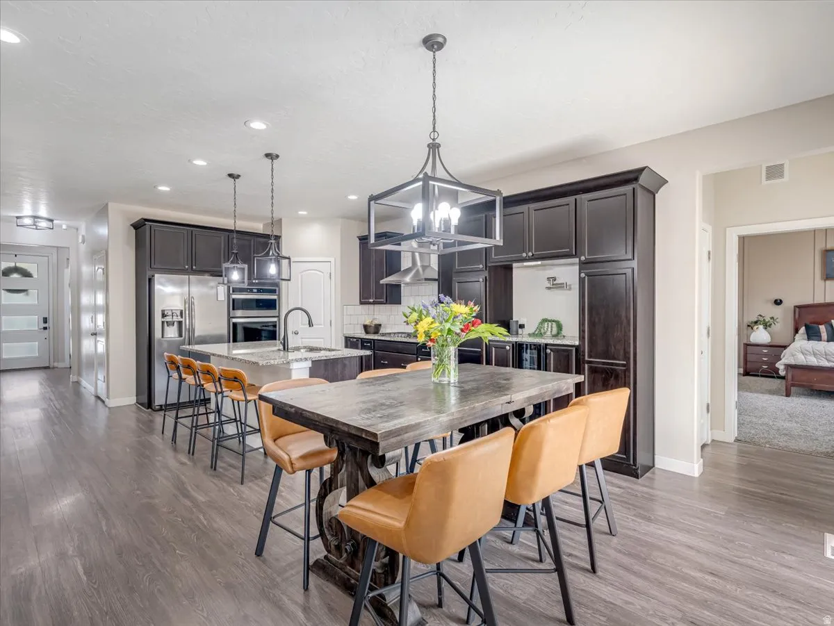 Gourmet kitchen featuring dark wood cabinetry, stainless steel appliances, granite countertops, and a large island with sink
