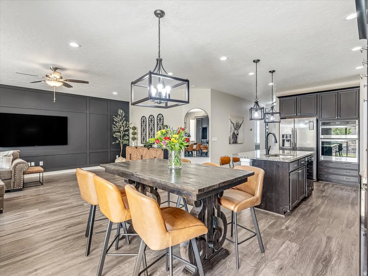 Spacious kitchen and dining area featuring wood-finish flooring, dark cabinetry, and recessed lighting