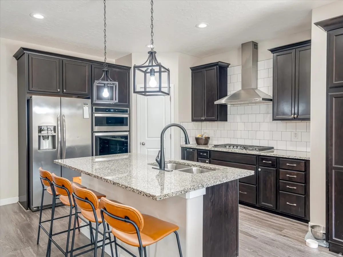 Kitchen featuring a central island with a double basin sink and a stone countertop