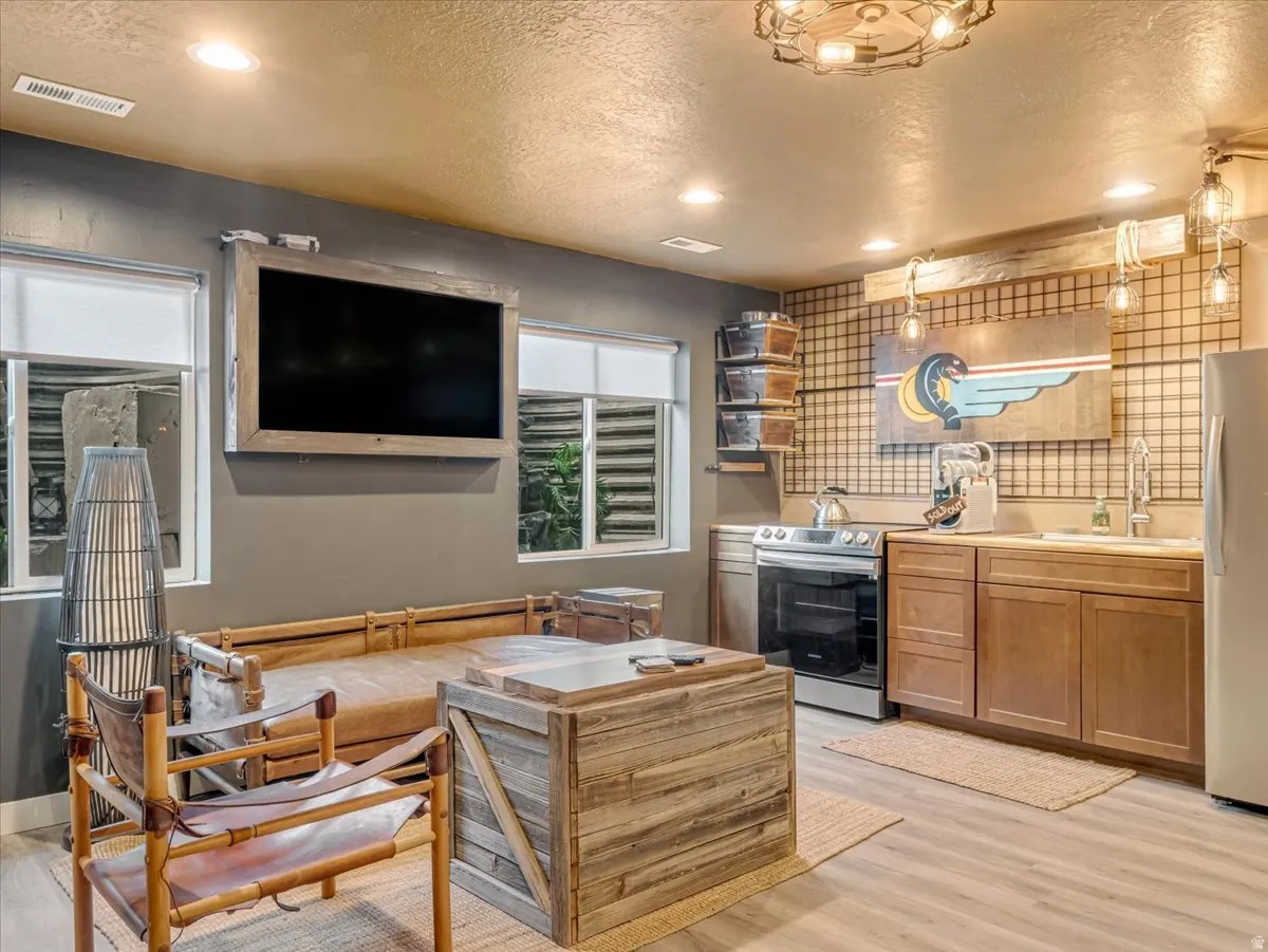 Lower-level living area with wood-finish flooring, a full kitchen featuring a stainless steel range, and recessed lighting