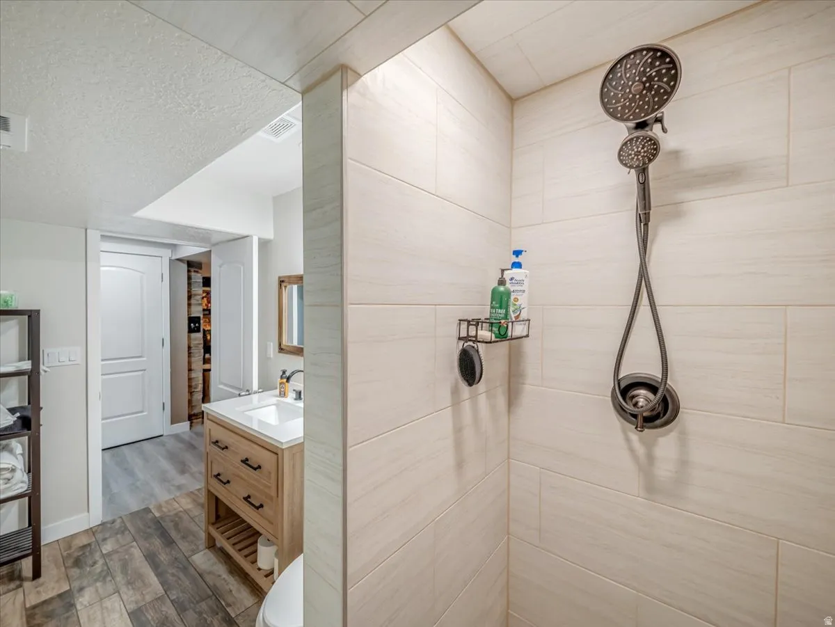 Shower area featuring light-toned large format wall tiling and a bronze-finish dual shower head system