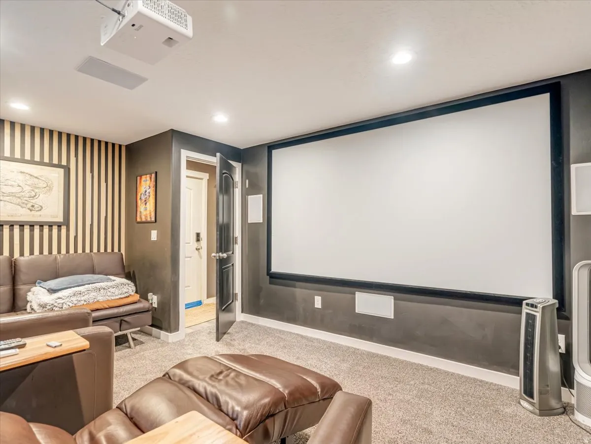 Dedicated media room featuring a large projection screen, mounted projector, recessed lighting, and built-in ceiling speakers