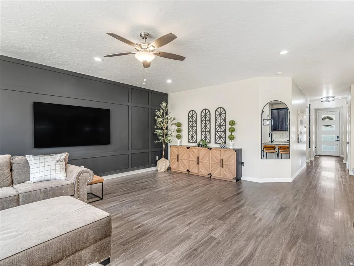 Spacious living area featuring plank wood-finish flooring, a contemporary ceiling fan, and recessed lighting