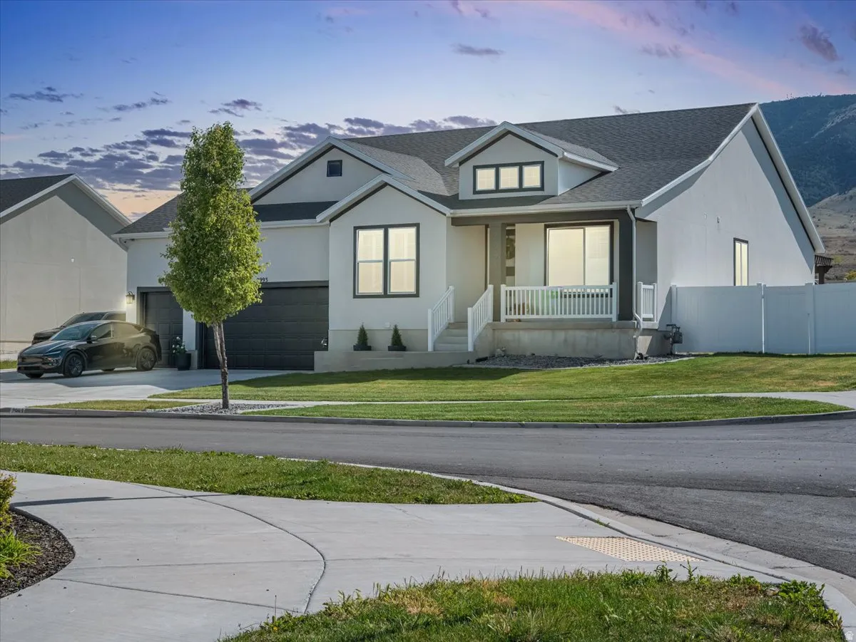 Contemporary-style residence featuring a white and gray exterior, a two-car garage with dark doors, a front porch with white railings, and a dormer window