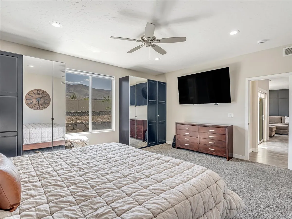 Spacious room featuring gray carpeting, a ceiling fan with integrated lighting, recessed lighting, and a large window presenting a mountain backdrop