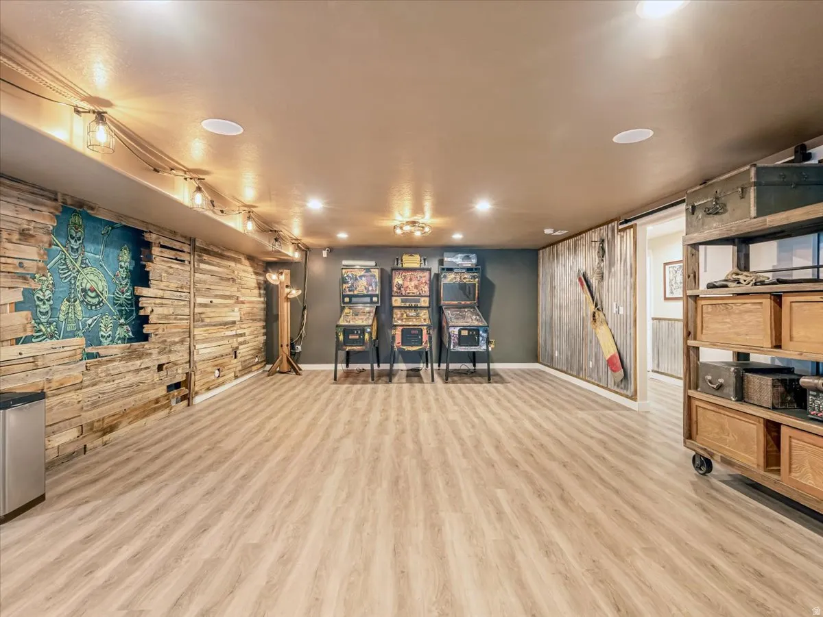Spacious interior room featuring wood-finish flooring, recessed lighting, and track lighting with exposed bulbs