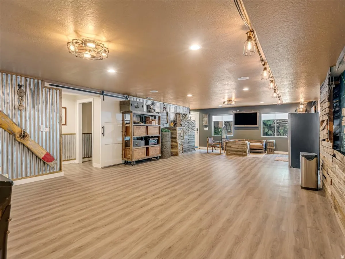 Spacious room featuring wood-finish flooring and a barn door entry