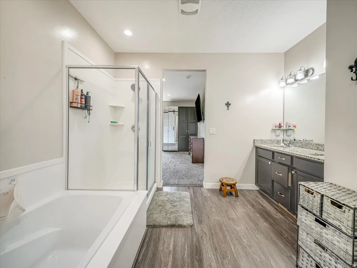 Contemporary bathroom featuring wood-finish flooring, a white soaking tub, and a glass-enclosed shower
