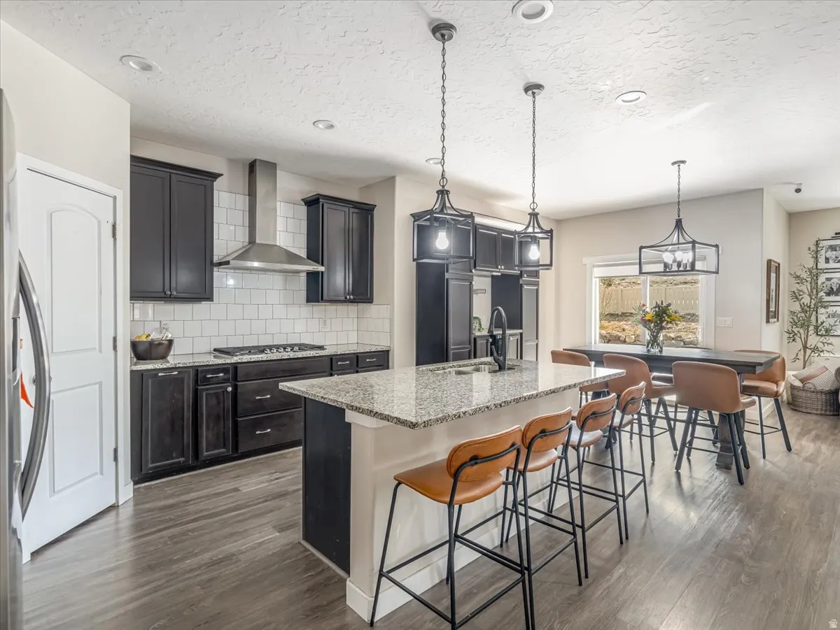 Modern kitchen featuring dark wood cabinetry, light granite countertops, a white subway tile backsplash, and stainless steel appliances