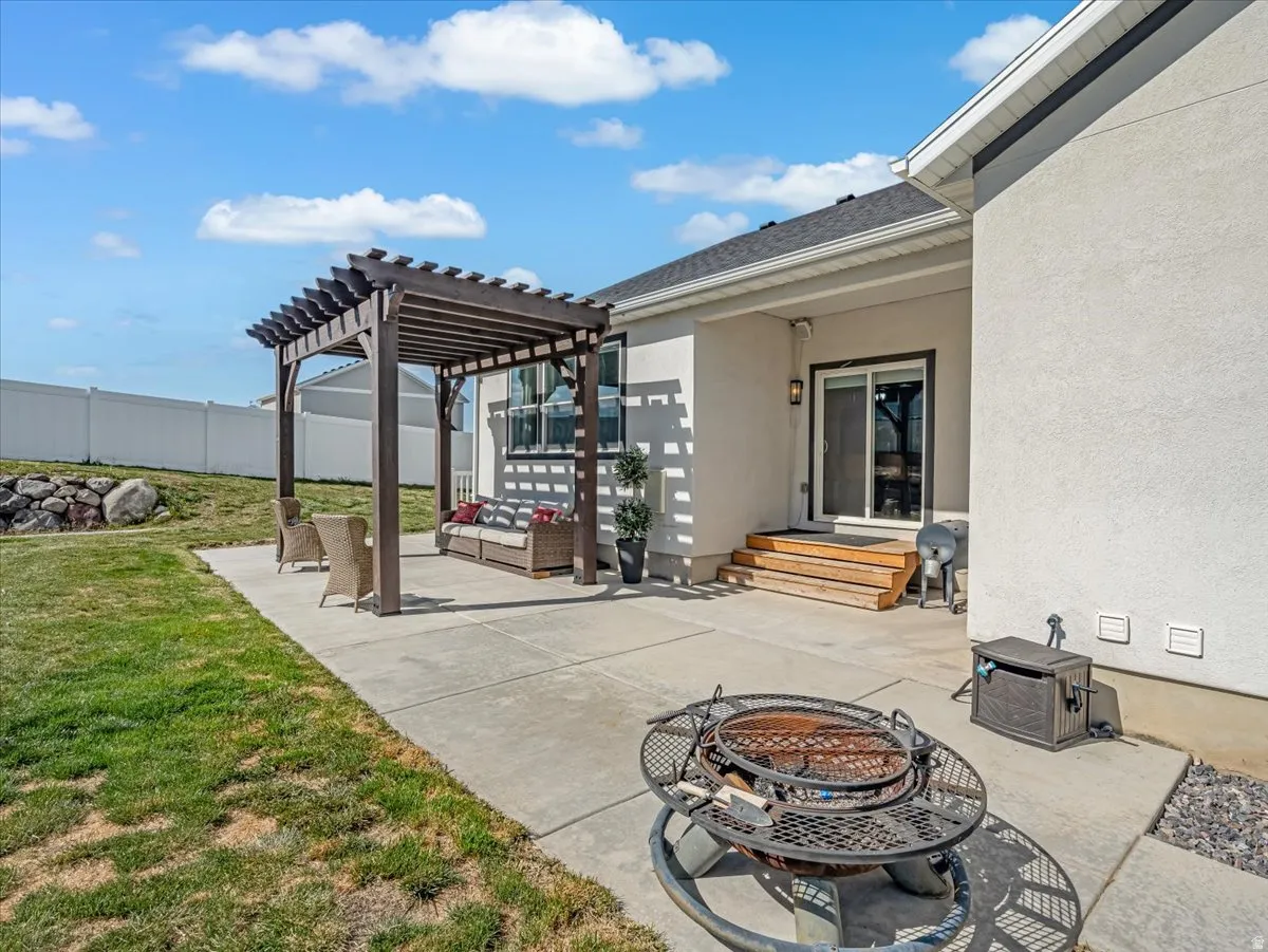 Exterior patio featuring a dark wood pergola, concrete surfacing, and a sliding glass door entry