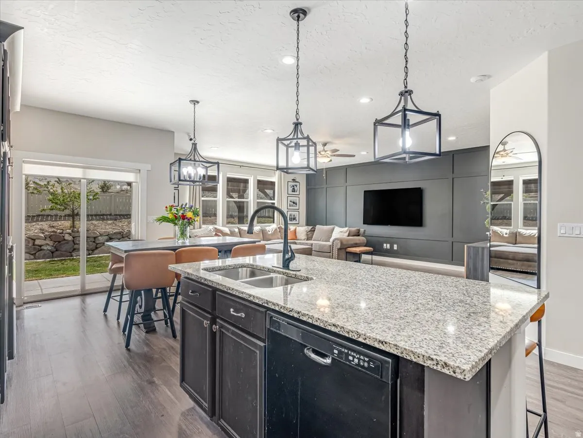 Gourmet kitchen island featuring a granite countertop, dual basin sink with a matte black faucet, and built-in dishwasher