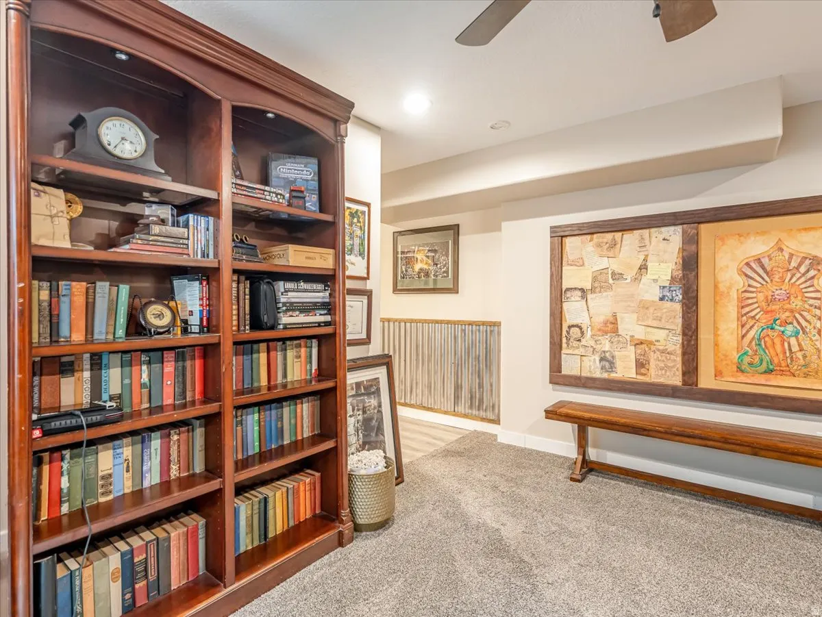 Built-in cherry wood shelving with integrated lighting, soft carpeting, flush-mounted ceiling lighting, and a ceiling fan