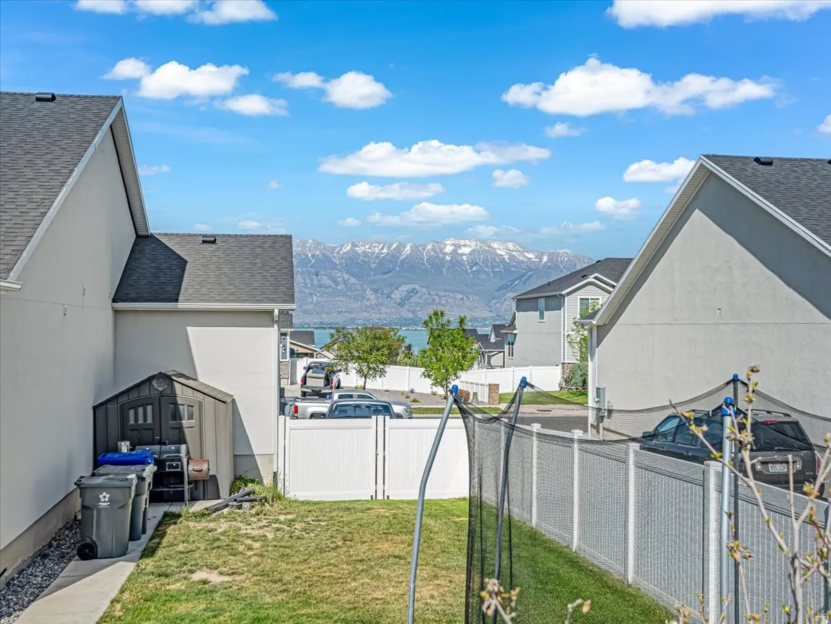 Fenced backyard with a grassy area and mountain scenery