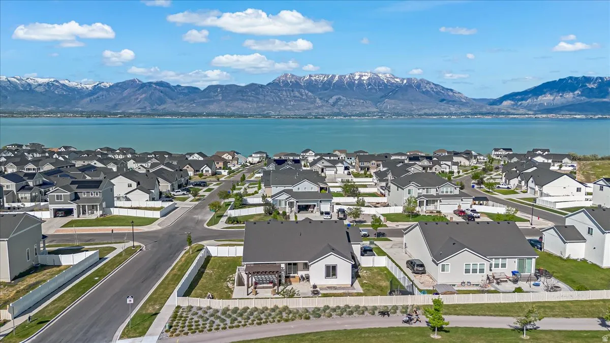 Expansive residential development featuring contemporary homes with dark shingle roofs, situated near a large body of water