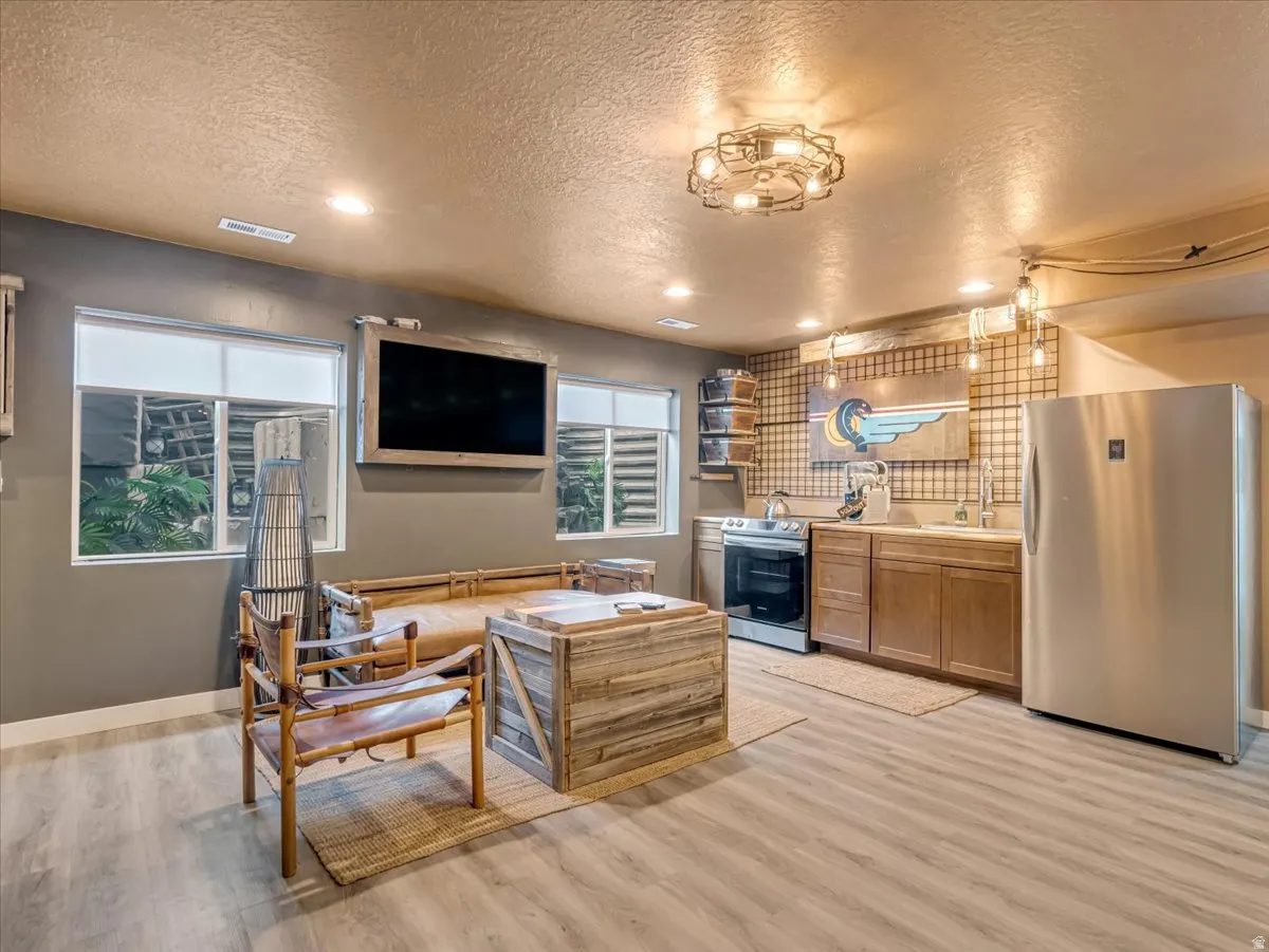 Recreational space featuring wood-finish flooring, a full kitchen with stainless steel appliances, recessed lighting, and a wall-mounted display