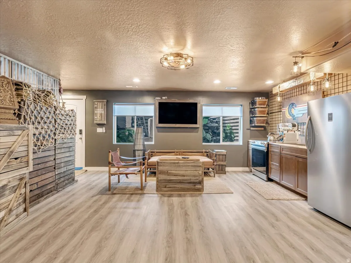 Spacious recreation room featuring light wood-finish flooring, recessed lighting, and a textured ceiling