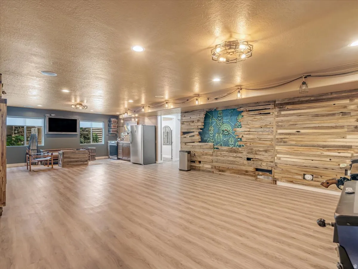 Spacious recreational area featuring plank wood-finish flooring, a full wood accent wall with integrated art, and recessed lighting