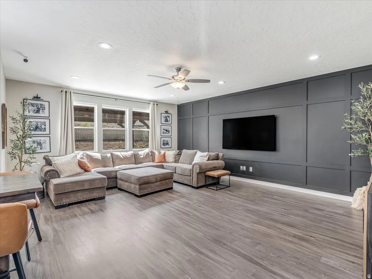 Spacious living area featuring wood-finish flooring, recessed lighting, and a ceiling fan