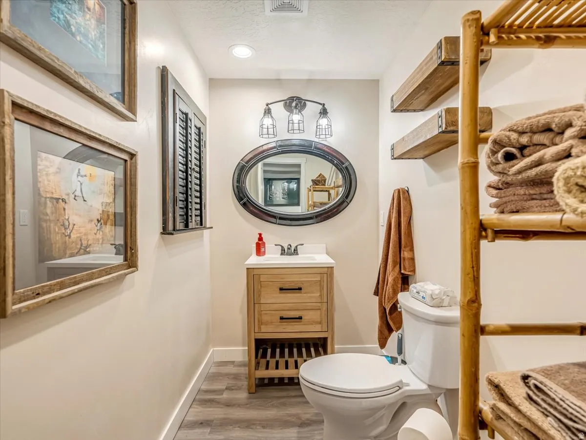 Bathroom featuring a wood-finish vanity with an integrated sink and a framed oval mirror