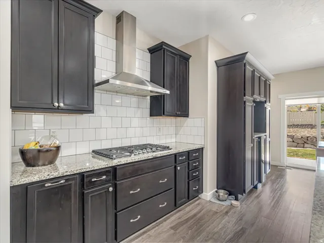 Kitchen featuring dark wood cabinetry, light-colored granite countertops, and a subway tile backsplash
