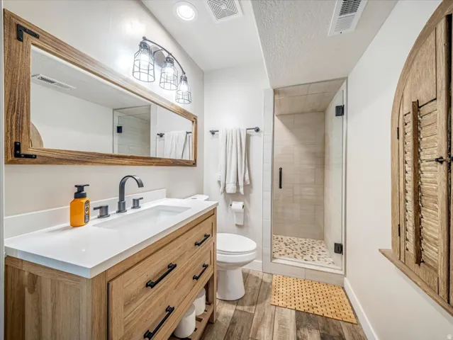 Bathroom featuring a wood-finish vanity with a white countertop, matte black faucet, and a rectangular mirror with a wood frame