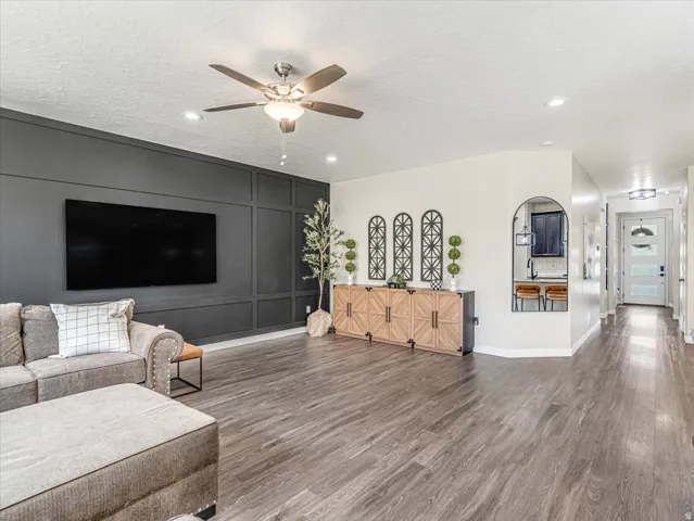 Spacious living area featuring plank wood-finish flooring, a contemporary ceiling fan, and recessed lighting