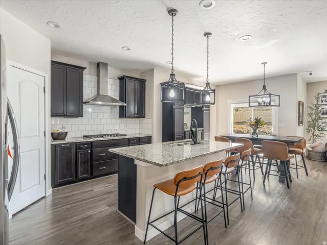 Modern kitchen featuring dark wood cabinetry, light granite countertops, a white subway tile backsplash, and stainless steel appliances