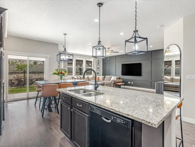 Gourmet kitchen island featuring a granite countertop, dual basin sink with a matte black faucet, and built-in dishwasher