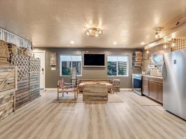 Spacious recreation room featuring light wood-finish flooring, recessed lighting, and a textured ceiling