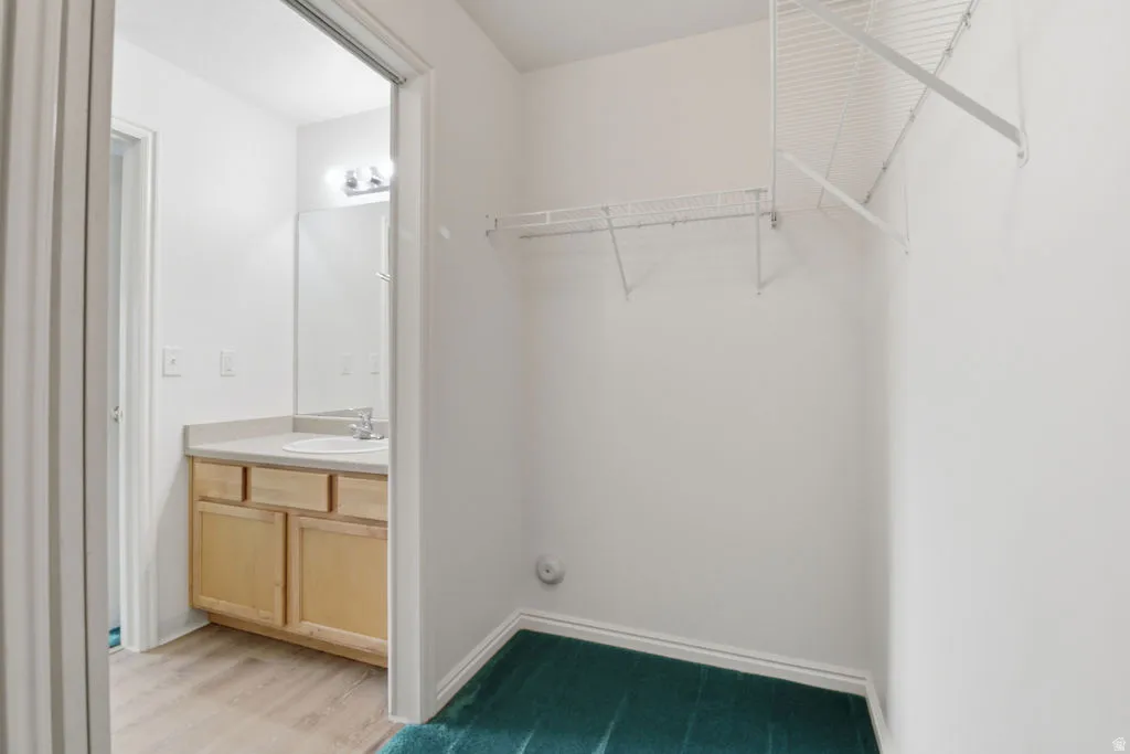 Walk-in closet featuring wire shelving and green carpet flooring