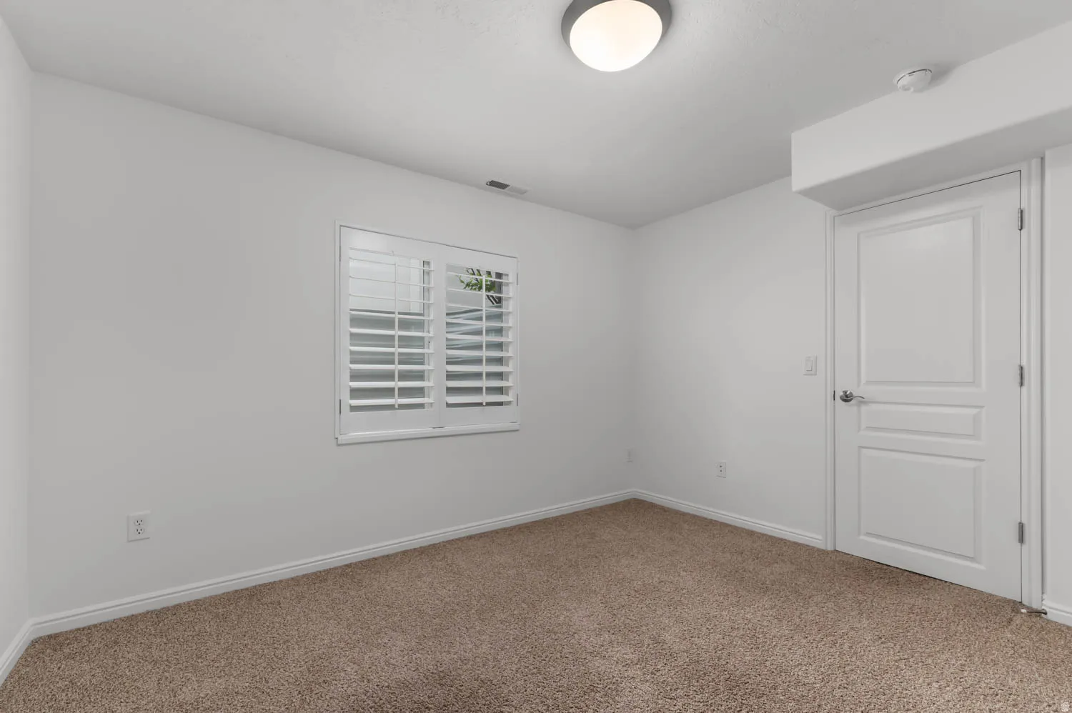 Neutral white wall paint with a window featuring white plantation shutters