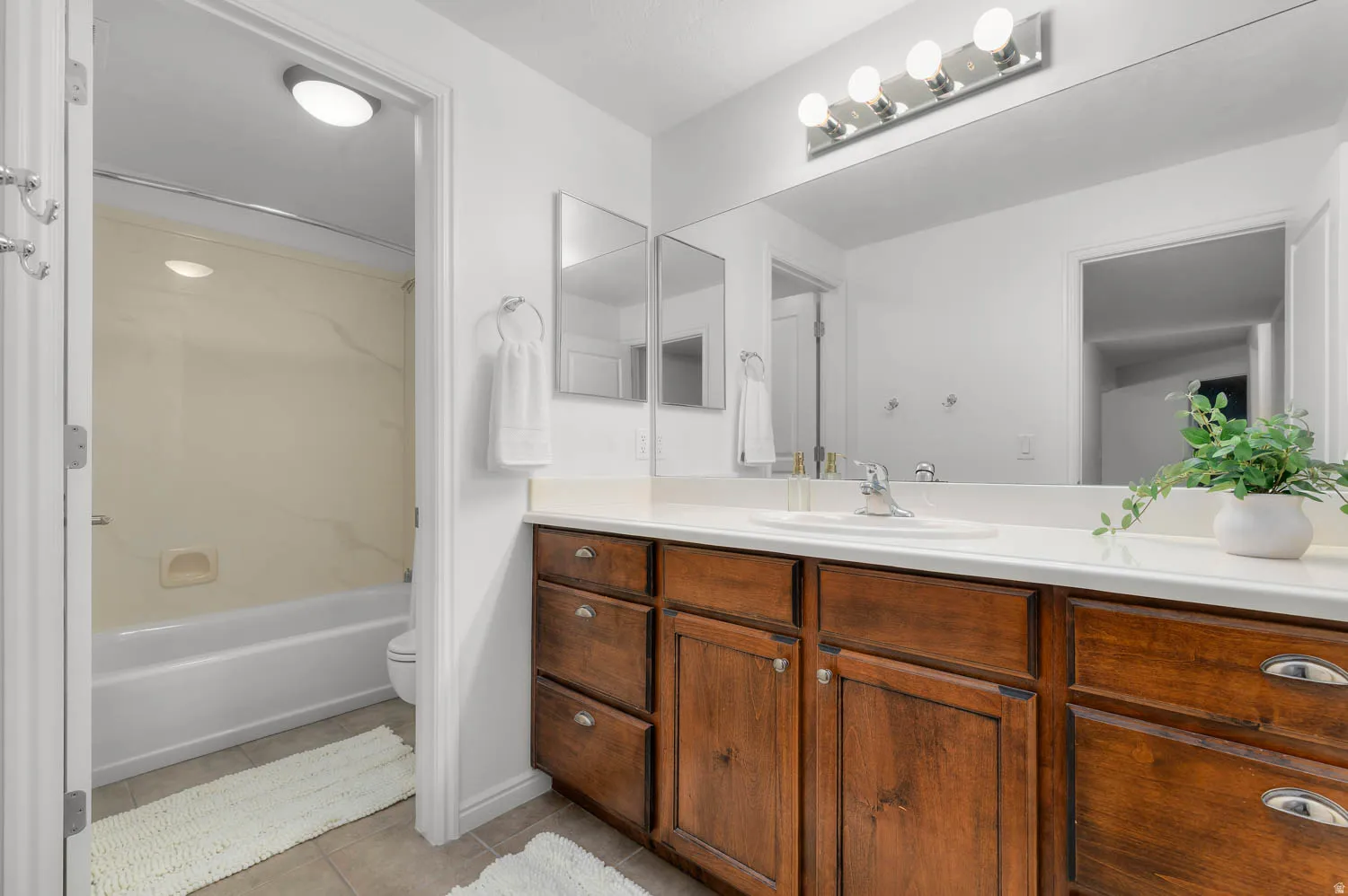 Bathroom featuring a spacious vanity with wood-finish cabinetry, a white countertop, and an integrated sink