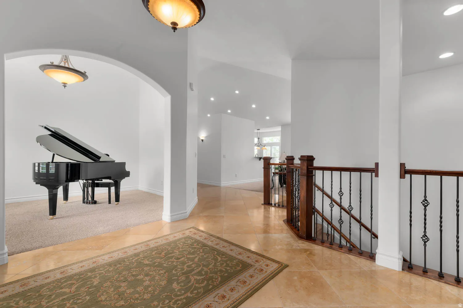 Spacious entryway with tile flooring, an arched doorway, recessed lighting, and a wood and wrought iron staircase railing