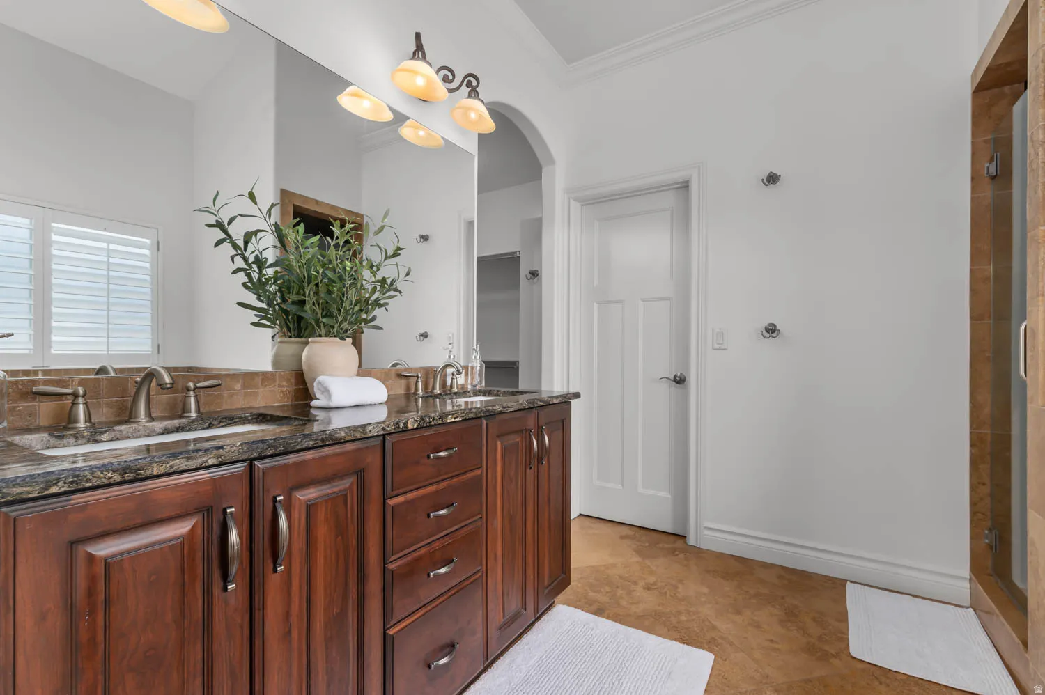 Dual sink vanity with dark wood cabinetry and stone countertops