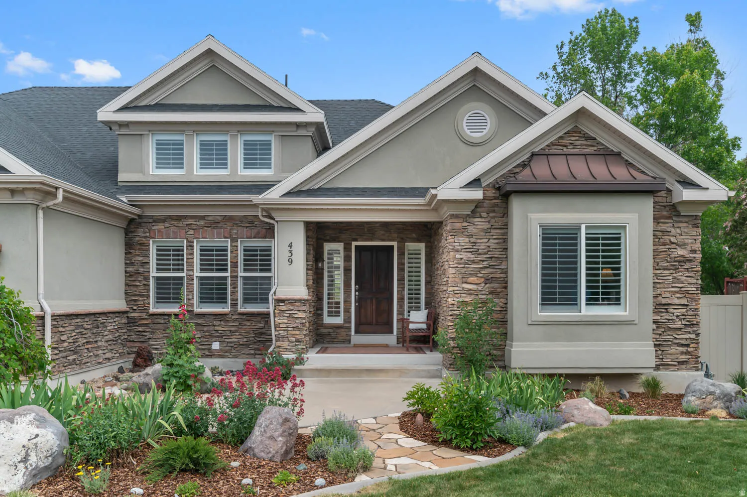 Stone veneer and stucco exterior featuring a prominent front entrance with a dark wood door and sidelights