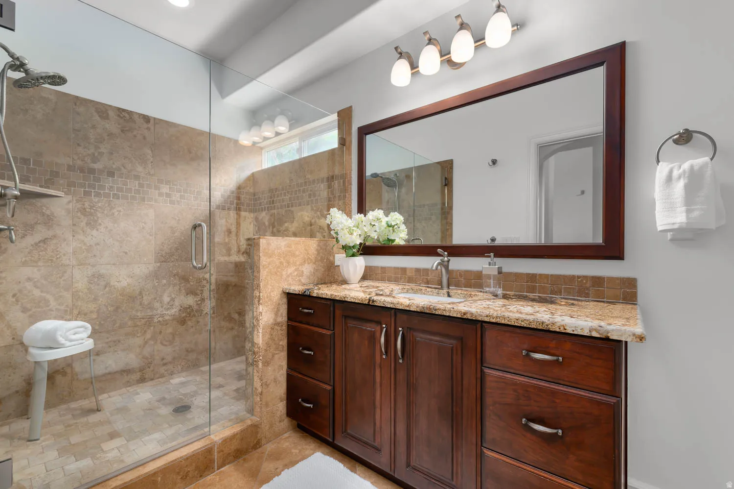 Walk-in shower with natural stone tile surround and glass enclosure