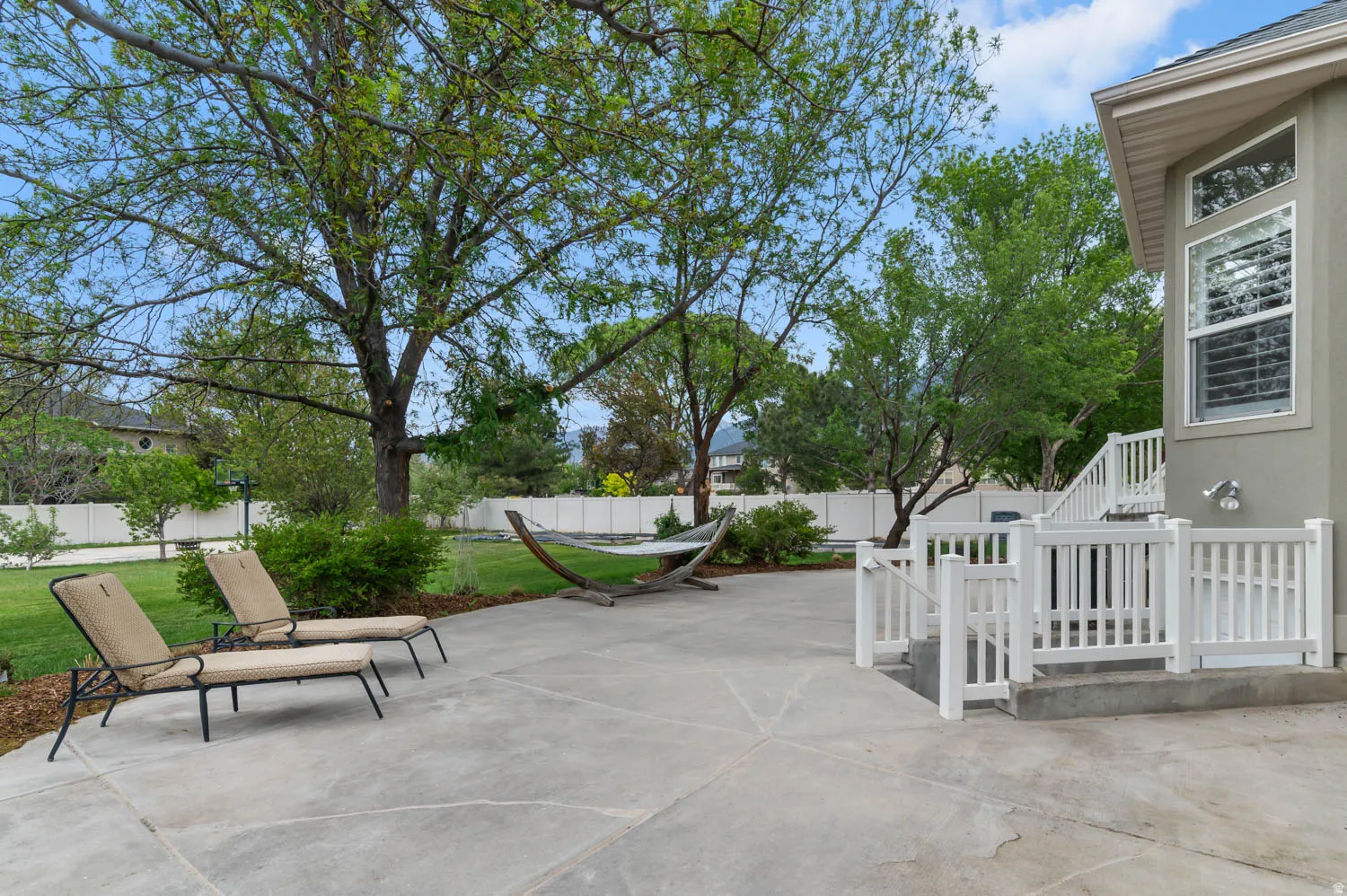Expansive concrete patio with white railing leading to the upper level