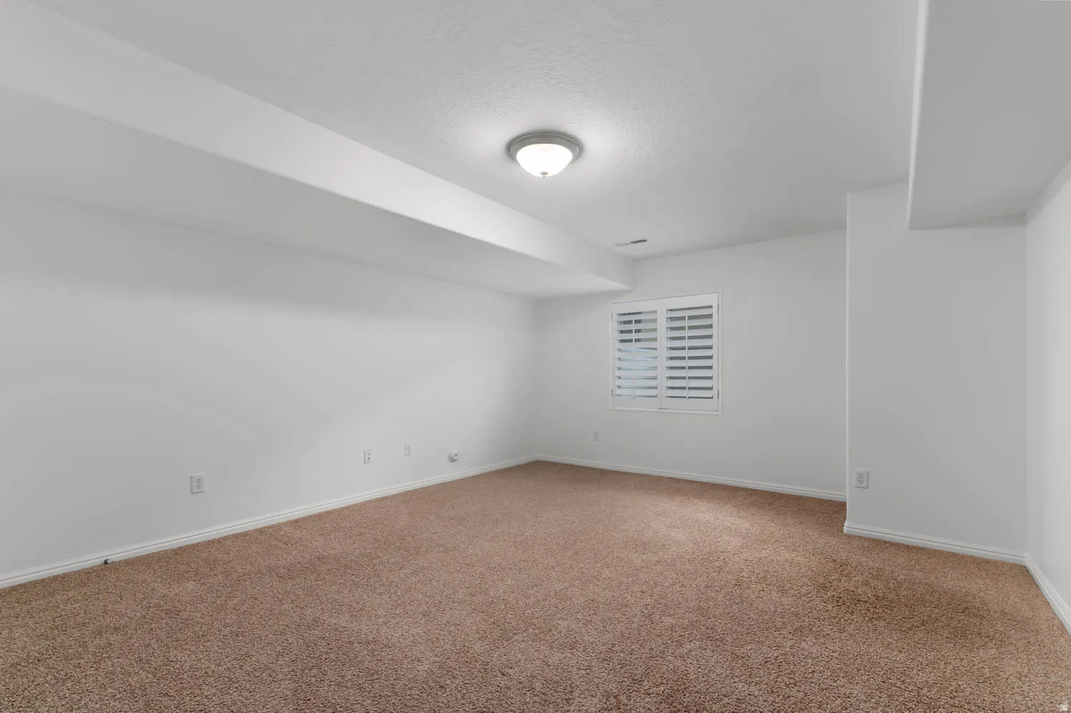 Spacious room featuring neutral carpeting and white walls